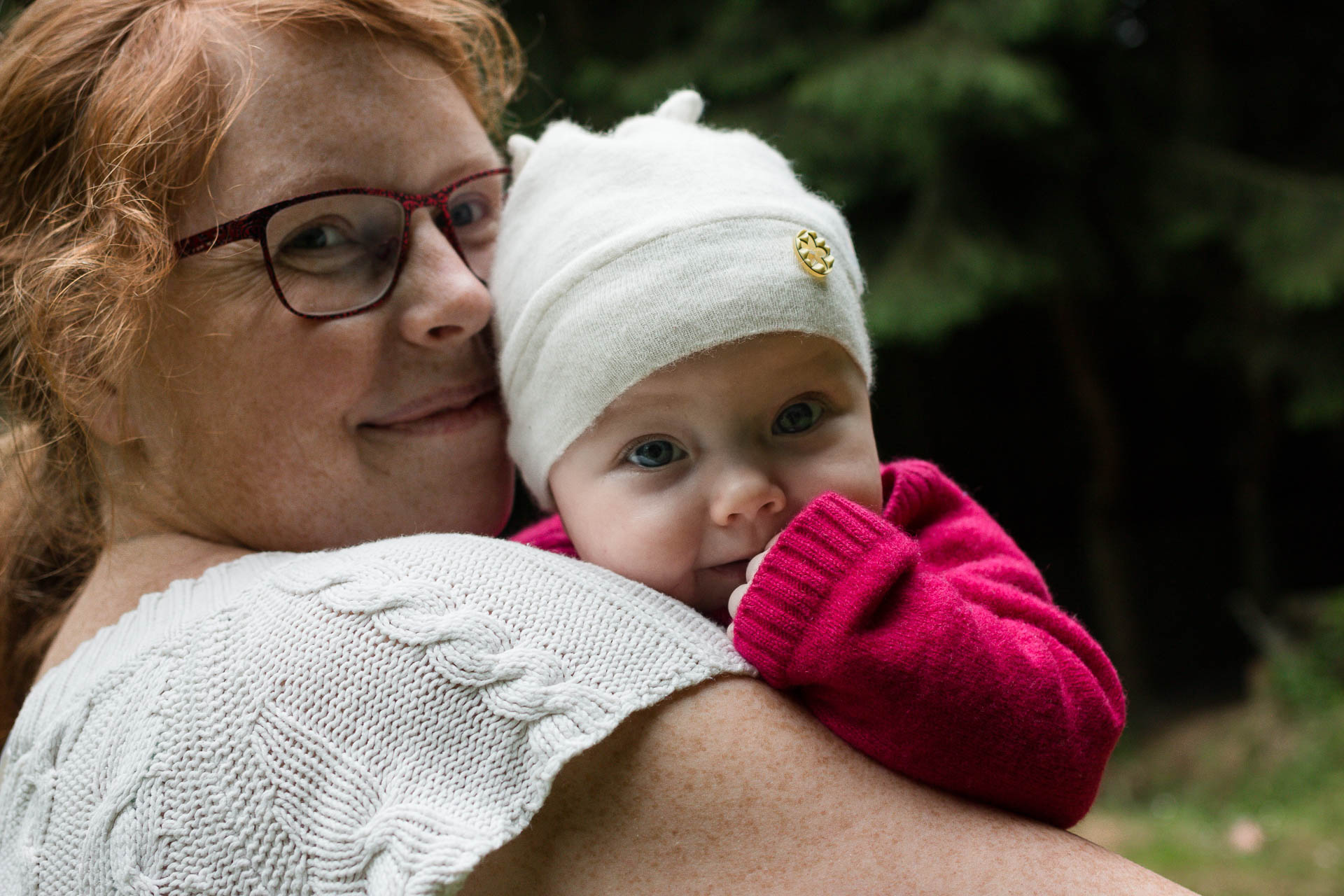 Usmívajicí se žena drží usměvavé miminko v bílé čepičce