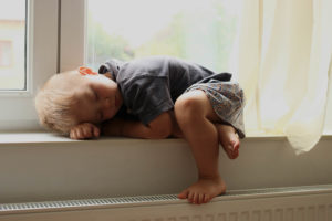Malý chlapec spící na okenním parapetu v domě