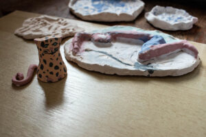 Detail ručně naglazovaných keramických výrobků, v popředí gepard