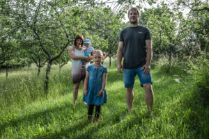 Young couple with two little children standing in an orchard