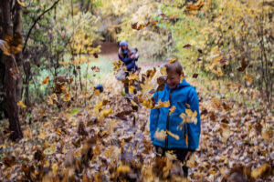 Leaves falling down on a child in autumn forest