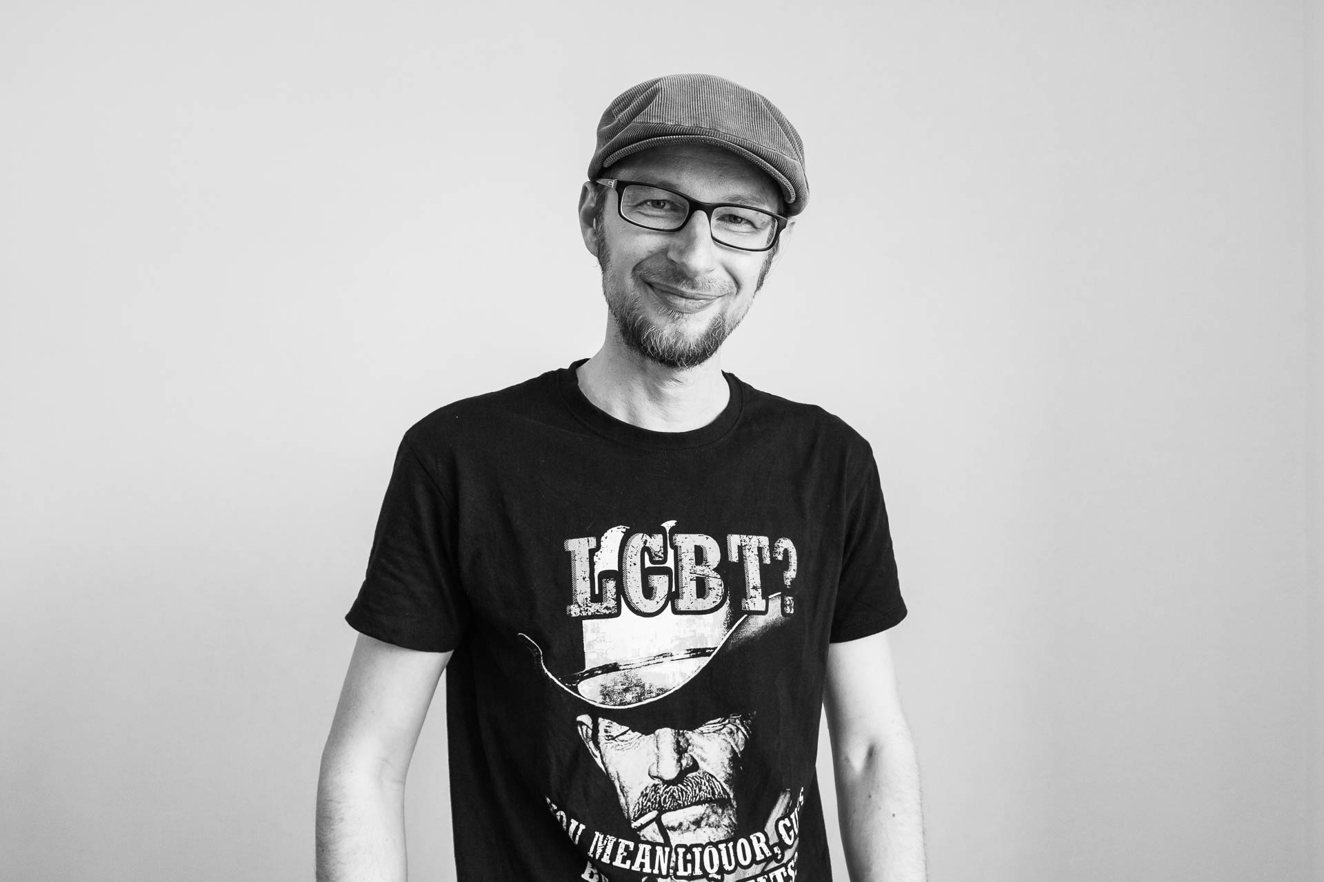 Portrét usmívajícího se mladého muže s brýlemi a v kšiltovce